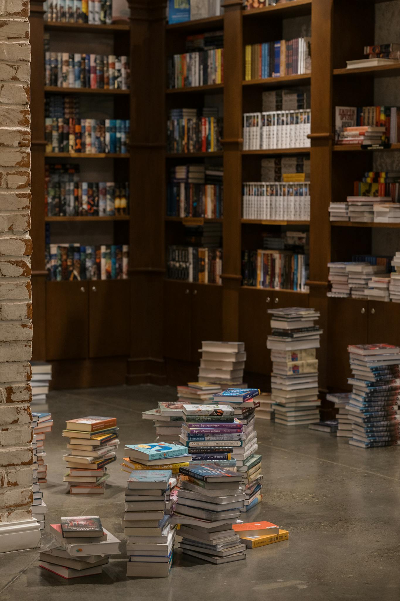 Warm library interior in Baku, Azerbaijan, featuring wooden shelves filled with books and stacks on the floor.